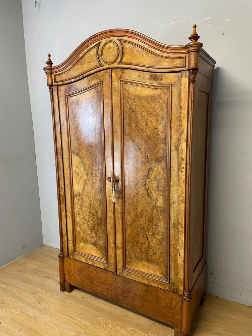 A nineteenth-century French figured walnut two-door armoire featuring an arched cornice with turned corner finials and a central circular moulding. View II