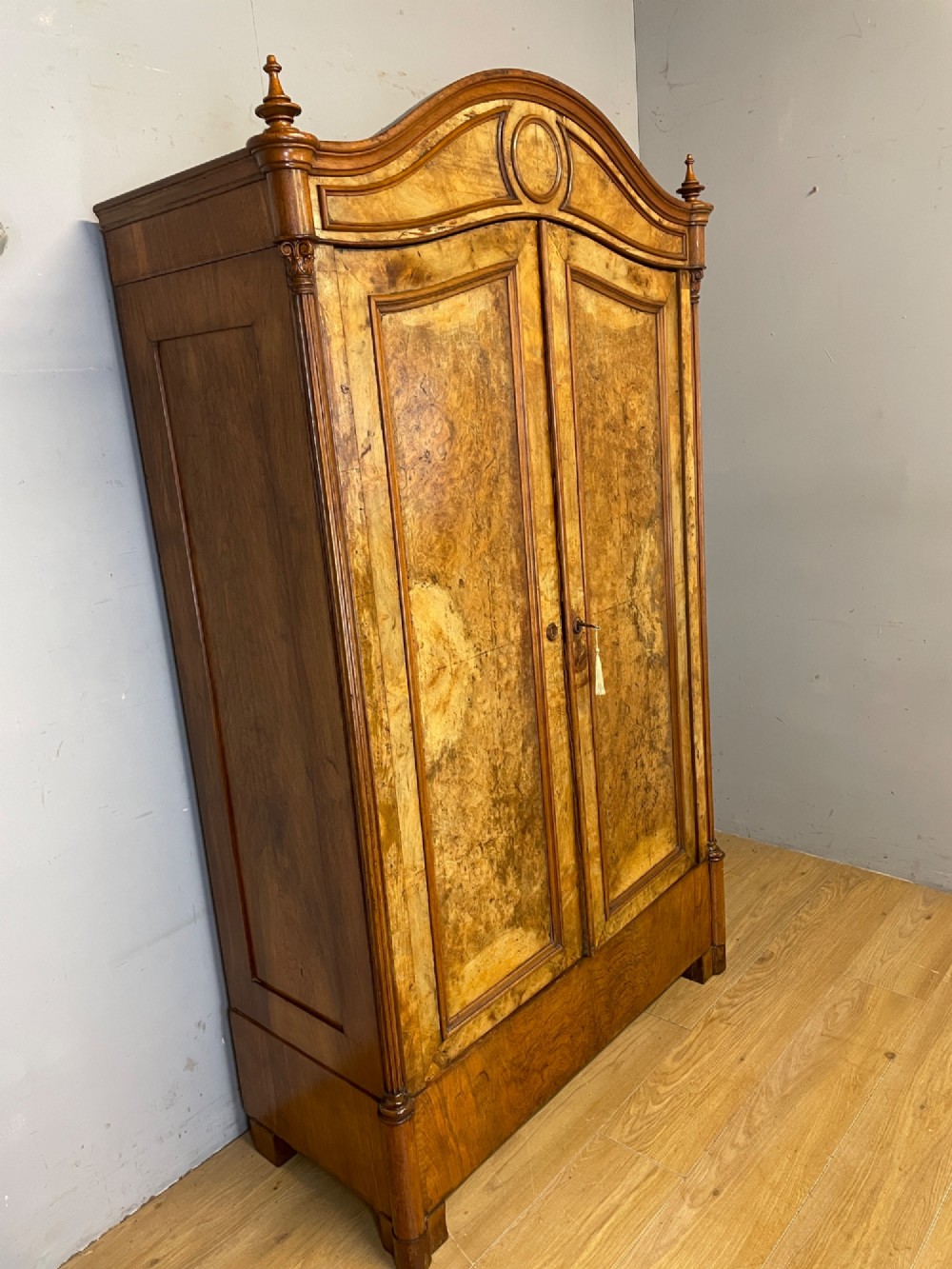 A nineteenth-century French figured walnut two-door armoire featuring an arched cornice with turned corner finials and a central circular moulding. View III