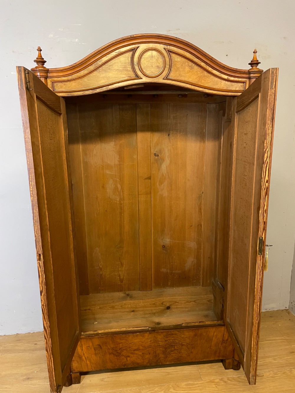 A nineteenth-century French figured walnut two-door armoire featuring an arched cornice with turned corner finials and a central circular moulding. View IV