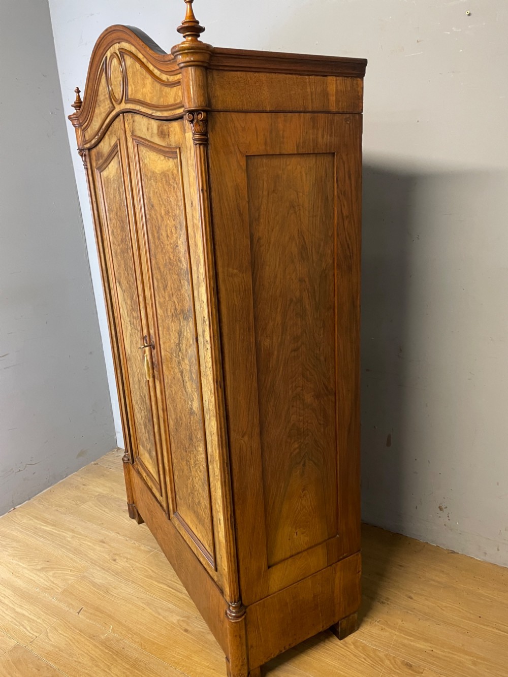 A nineteenth-century French figured walnut two-door armoire featuring an arched cornice with turned corner finials and a central circular moulding. View VIII