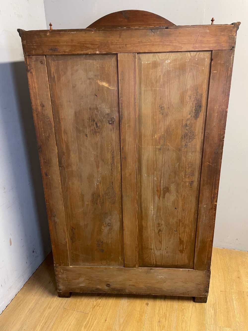 A nineteenth-century French figured walnut two-door armoire featuring an arched cornice with turned corner finials and a central circular moulding. View X