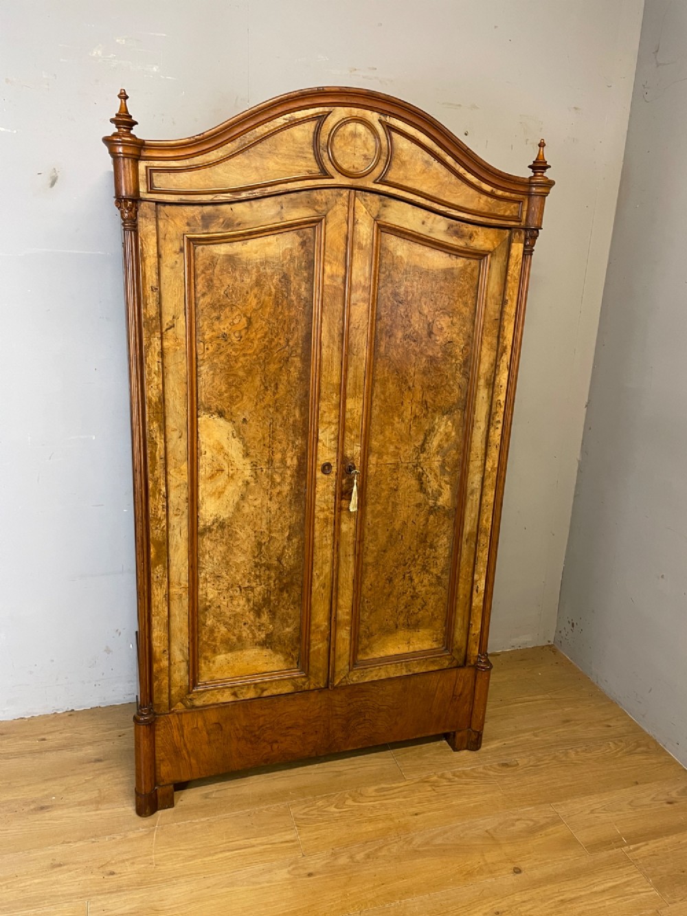 A nineteenth-century French figured walnut two-door armoire featuring an arched cornice with turned corner finials and a central circular moulding. View XI