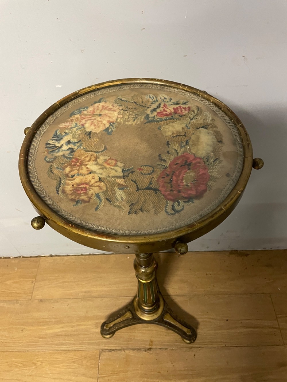 A 19th-century gilt and ebonised torchere stand featuring a circular needlework top, a turned column stem, and tripod feet. View II