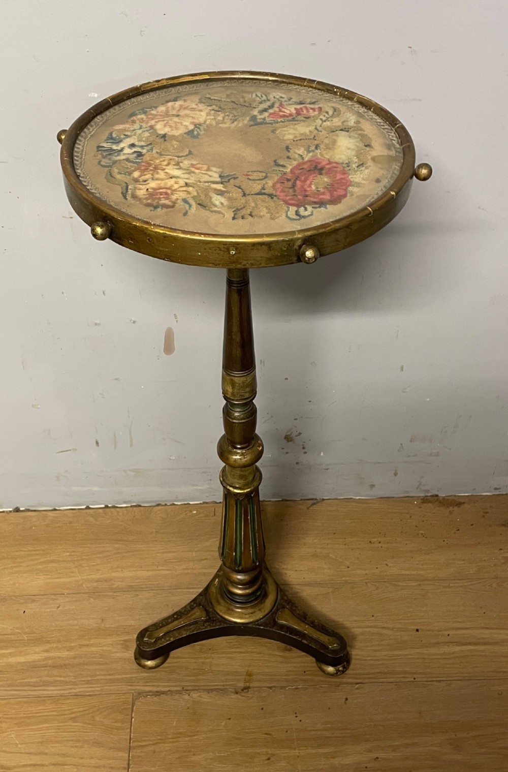 A 19th-century gilt and ebonised torchere stand featuring a circular needlework top, a turned column stem, and tripod feet. View X
