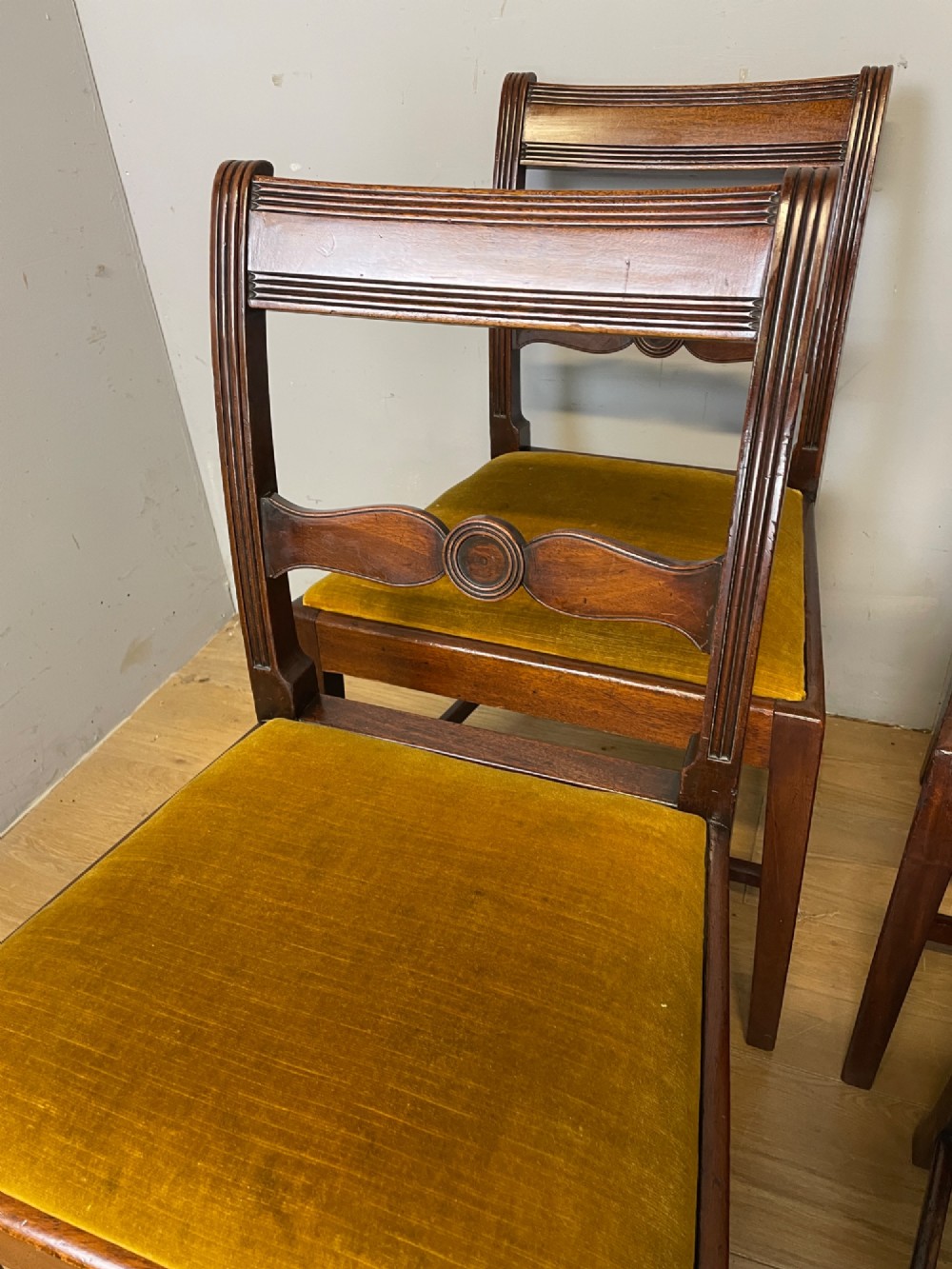 A set of six Georgian mahogany dining chairs featuring reeded frames, carved back rails with roundels, square legs with stretchers, and gold velvet seats. View III