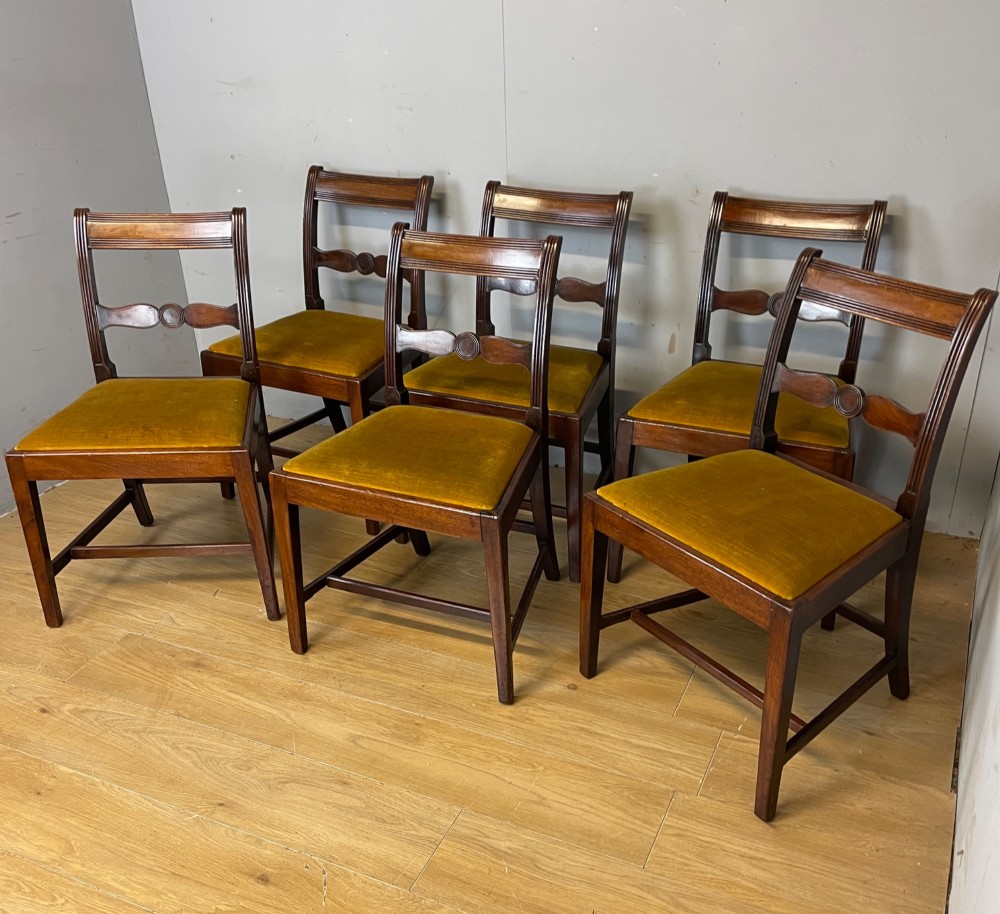 A set of six Georgian mahogany dining chairs featuring reeded frames, carved back rails with roundels, square legs with stretchers, and gold velvet seats. View XII
