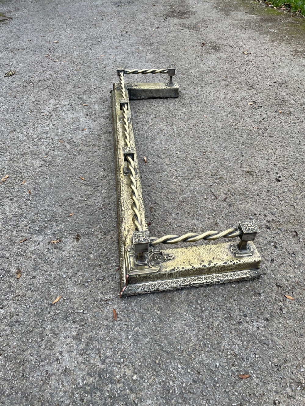 A 19th-century brass fireplace fender featuring a twisted top rail supported by four square columns over an embossed base. View IV