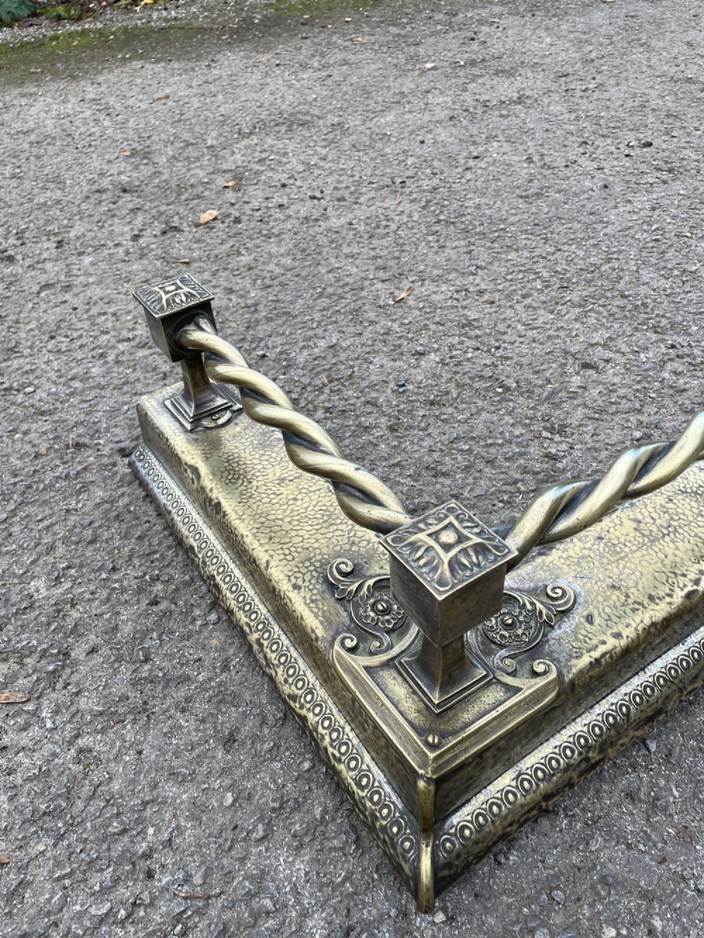 A 19th-century brass fireplace fender featuring a twisted top rail supported by four square columns over an embossed base. View VI