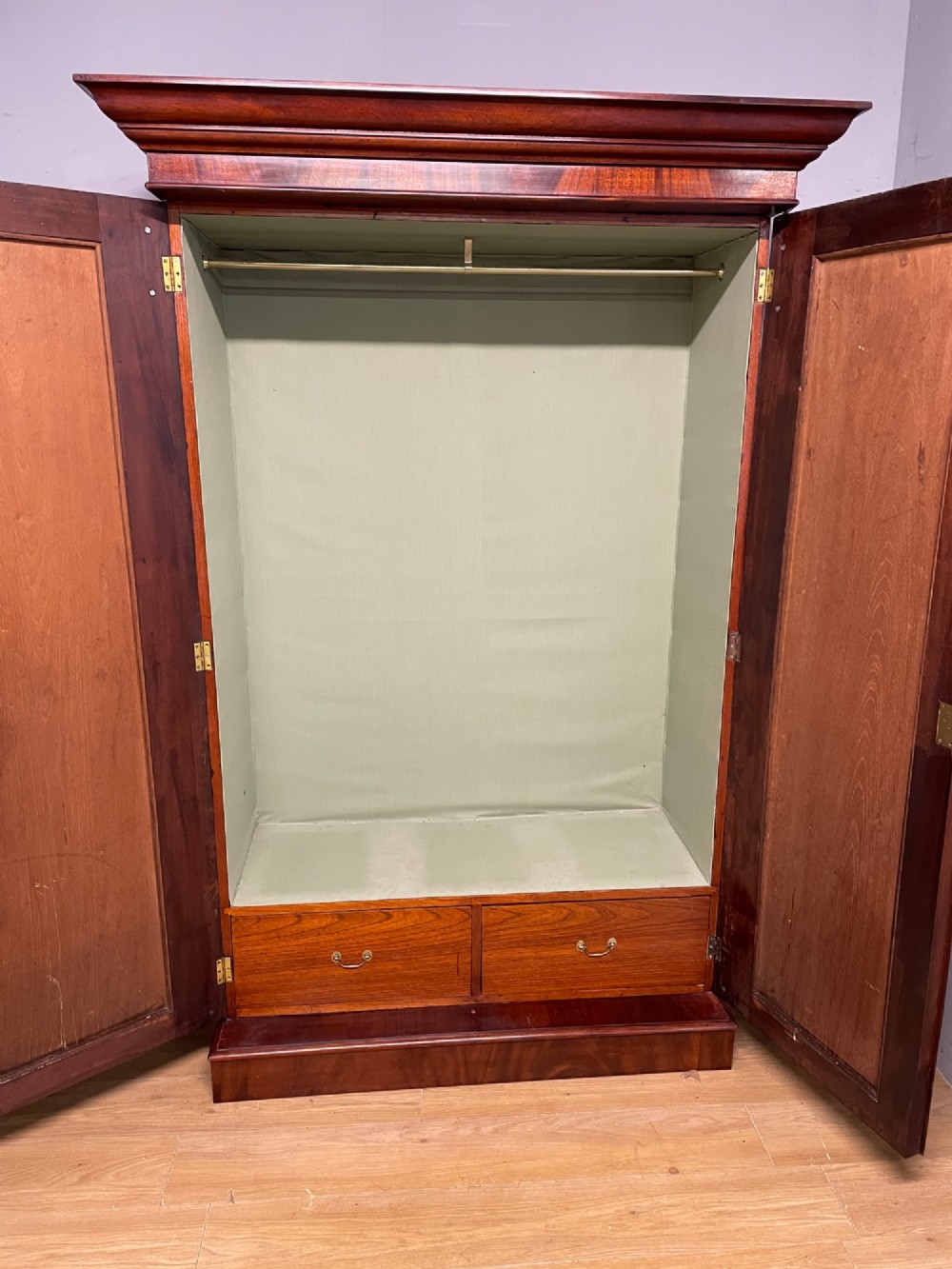 A 19th-century double wardrobe constructed from flame mahogany featuring two arched panelled doors, carved corbel accents, a moulded cornice, and a flat plinth base. View VII