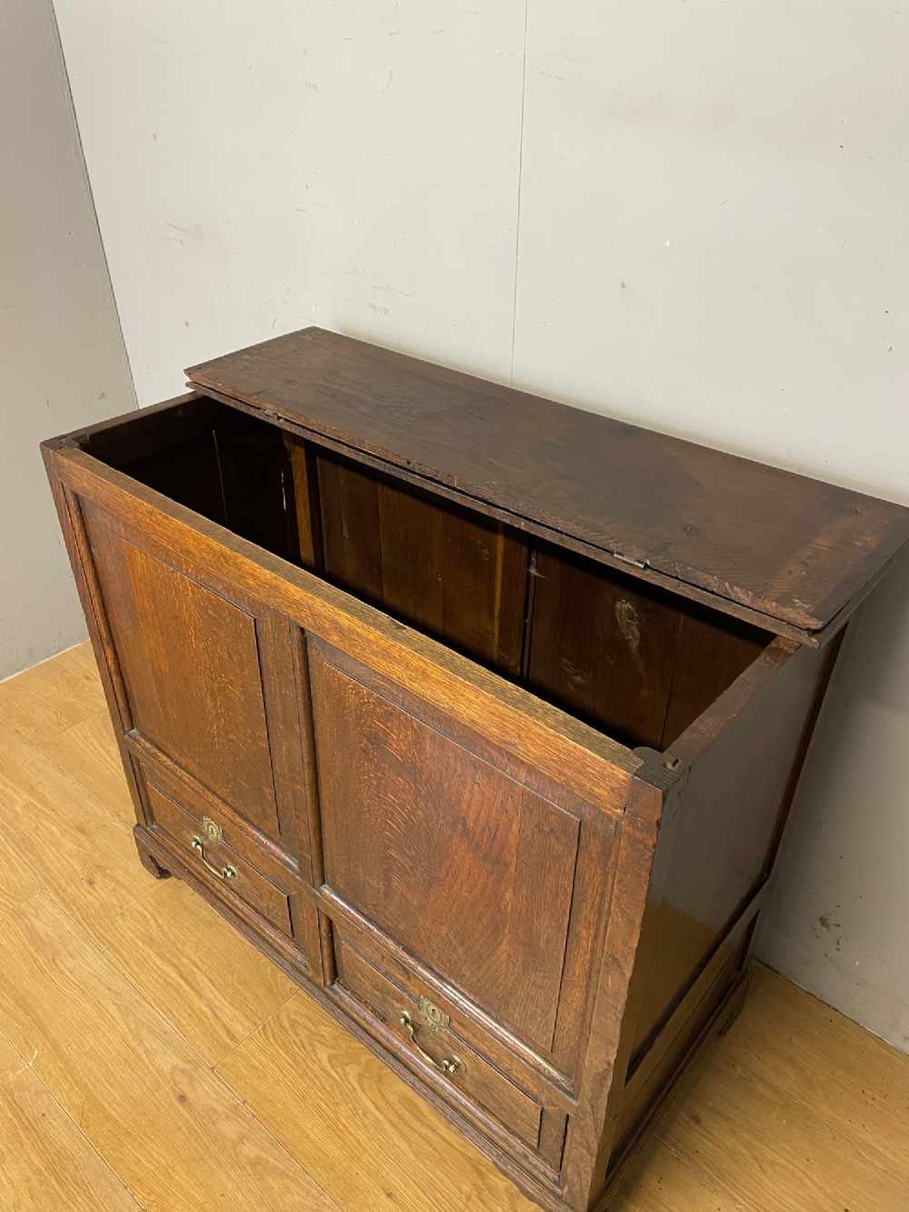 A nineteenth-century dark oak mule chest featuring a hinged lid, two front raised field panels, and two lower drawers with brass swan-neck handles. View IV