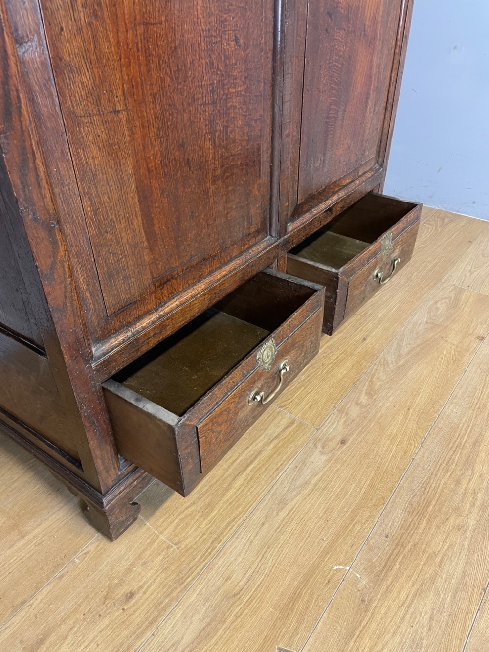 A nineteenth-century dark oak mule chest featuring a hinged lid, two front raised field panels, and two lower drawers with brass swan-neck handles. View VII