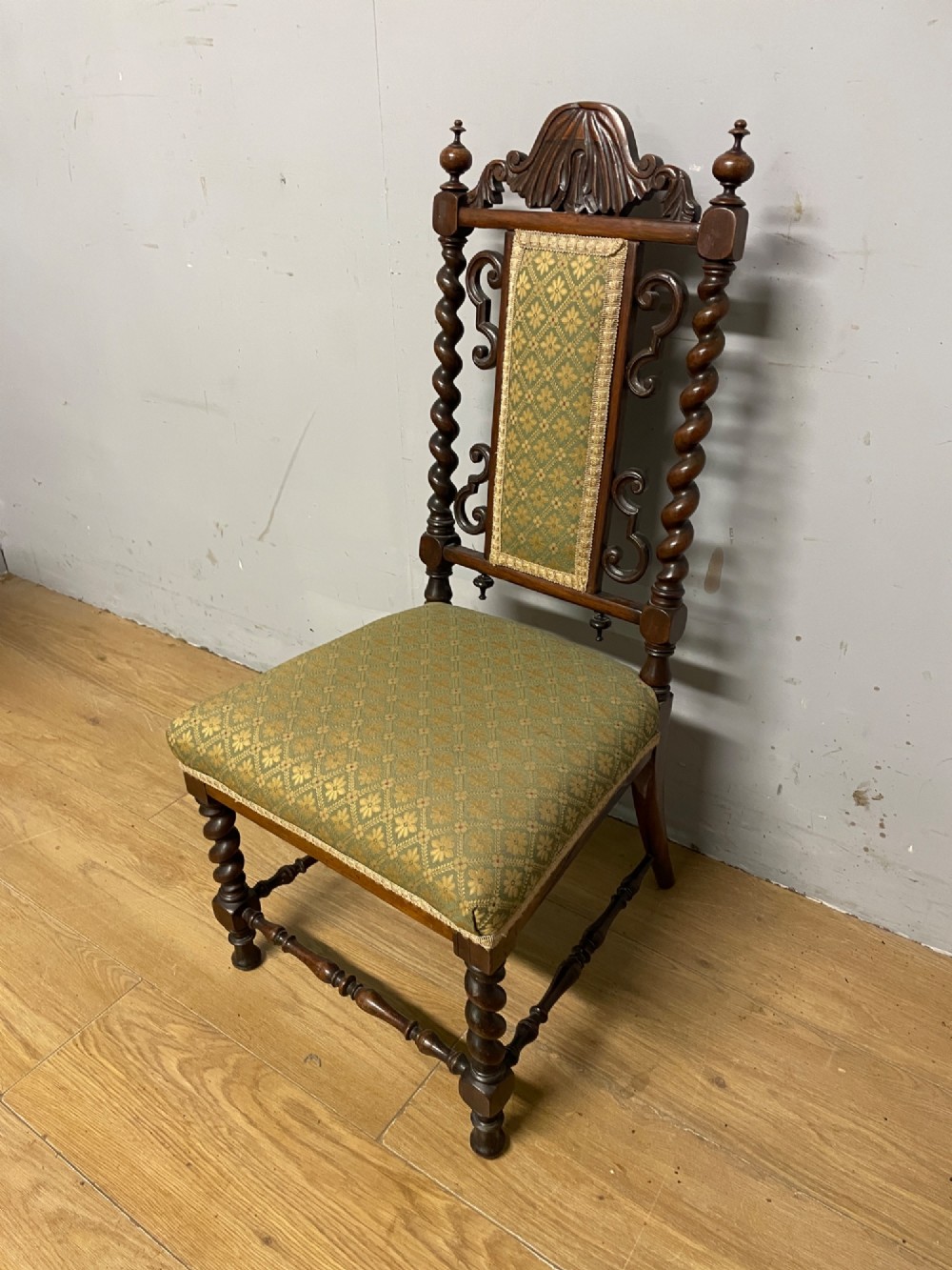 A nineteenth-century carved rosewood nursing chair featuring barley twist uprights, scrollwork cresting, and patterned green upholstery on the seat and back panel. View II