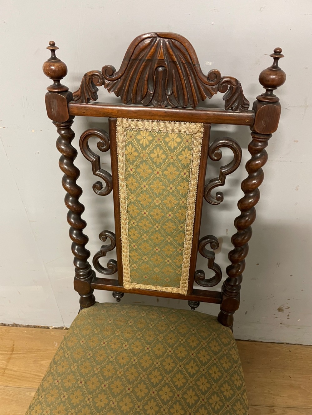 A nineteenth-century carved rosewood nursing chair featuring barley twist uprights, scrollwork cresting, and patterned green upholstery on the seat and back panel. View III
