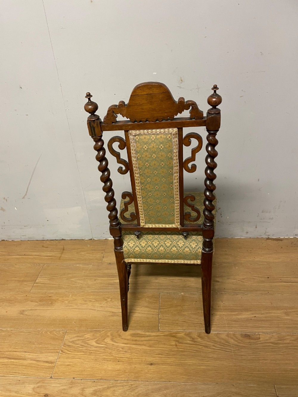 A nineteenth-century carved rosewood nursing chair featuring barley twist uprights, scrollwork cresting, and patterned green upholstery on the seat and back panel. View VI