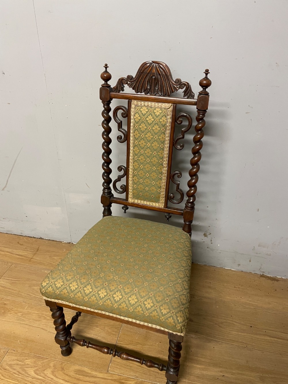 A nineteenth-century carved rosewood nursing chair featuring barley twist uprights, scrollwork cresting, and patterned green upholstery on the seat and back panel. View VII