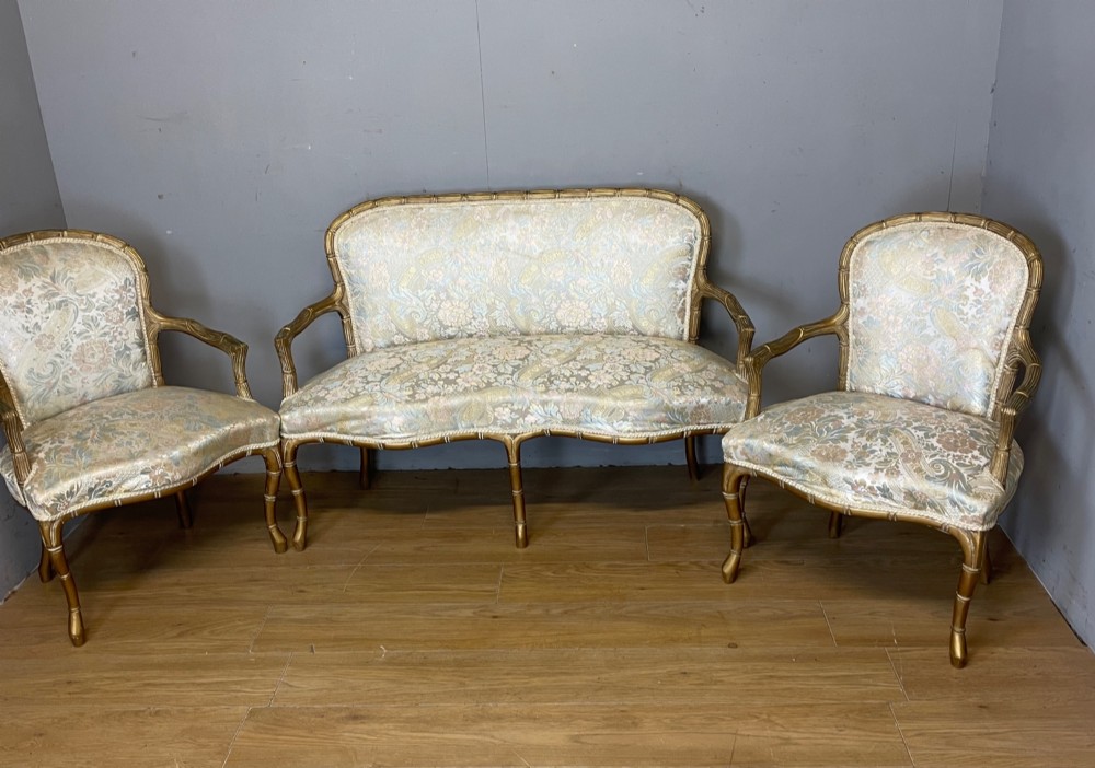 A three-piece Edwardian French style giltwood salon suite comprising a two-seater sofa and two matching armchairs upholstered in patterned cream silk fabric. View II