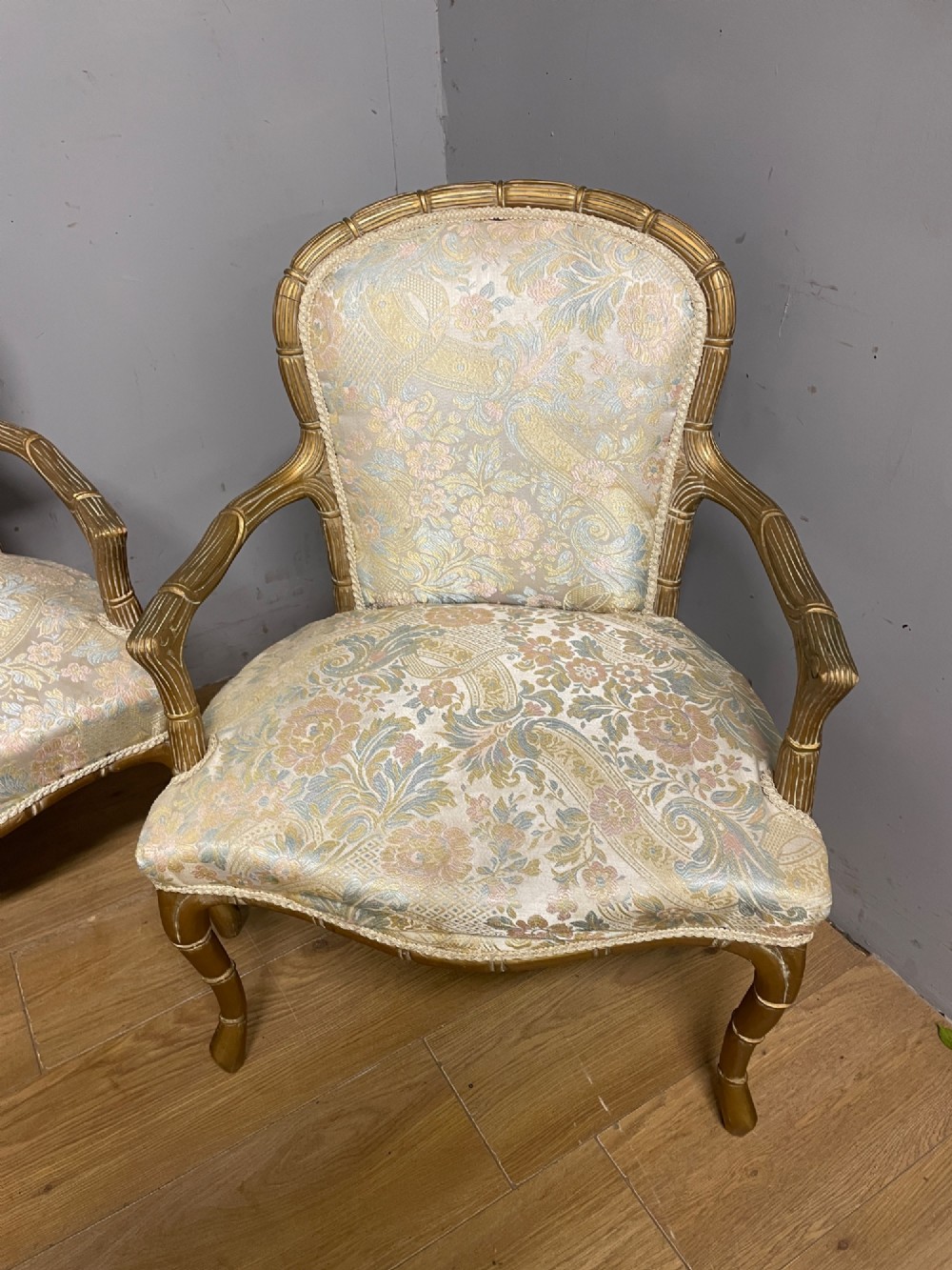 A three-piece Edwardian French style giltwood salon suite comprising a two-seater sofa and two matching armchairs upholstered in patterned cream silk fabric. View III