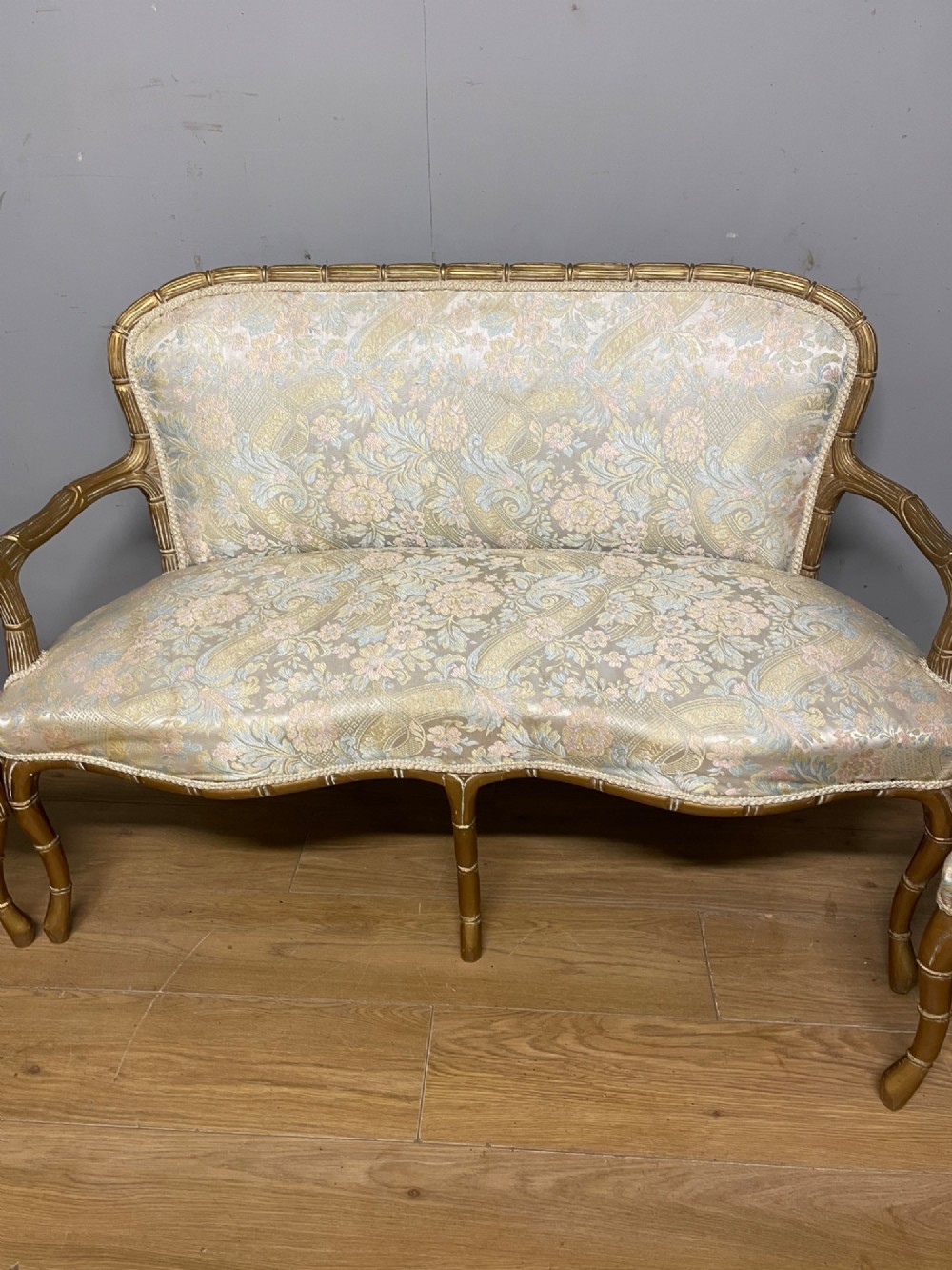 A three-piece Edwardian French style giltwood salon suite comprising a two-seater sofa and two matching armchairs upholstered in patterned cream silk fabric. View IV