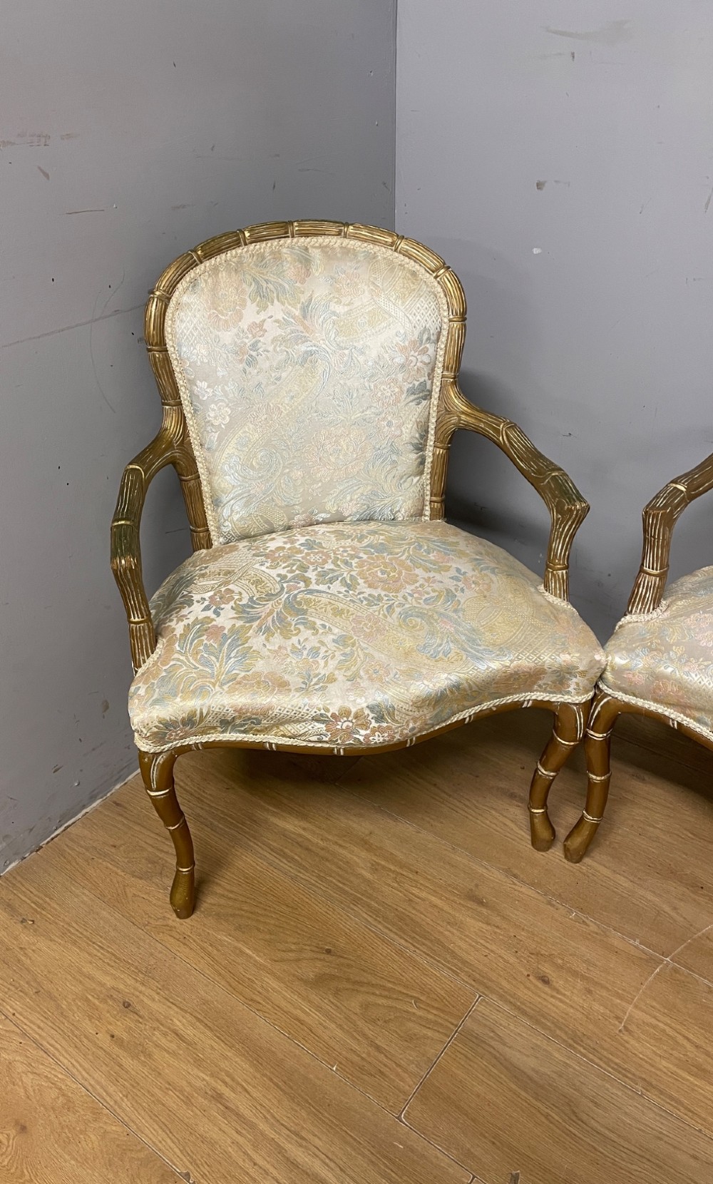 A three-piece Edwardian French style giltwood salon suite comprising a two-seater sofa and two matching armchairs upholstered in patterned cream silk fabric. View V