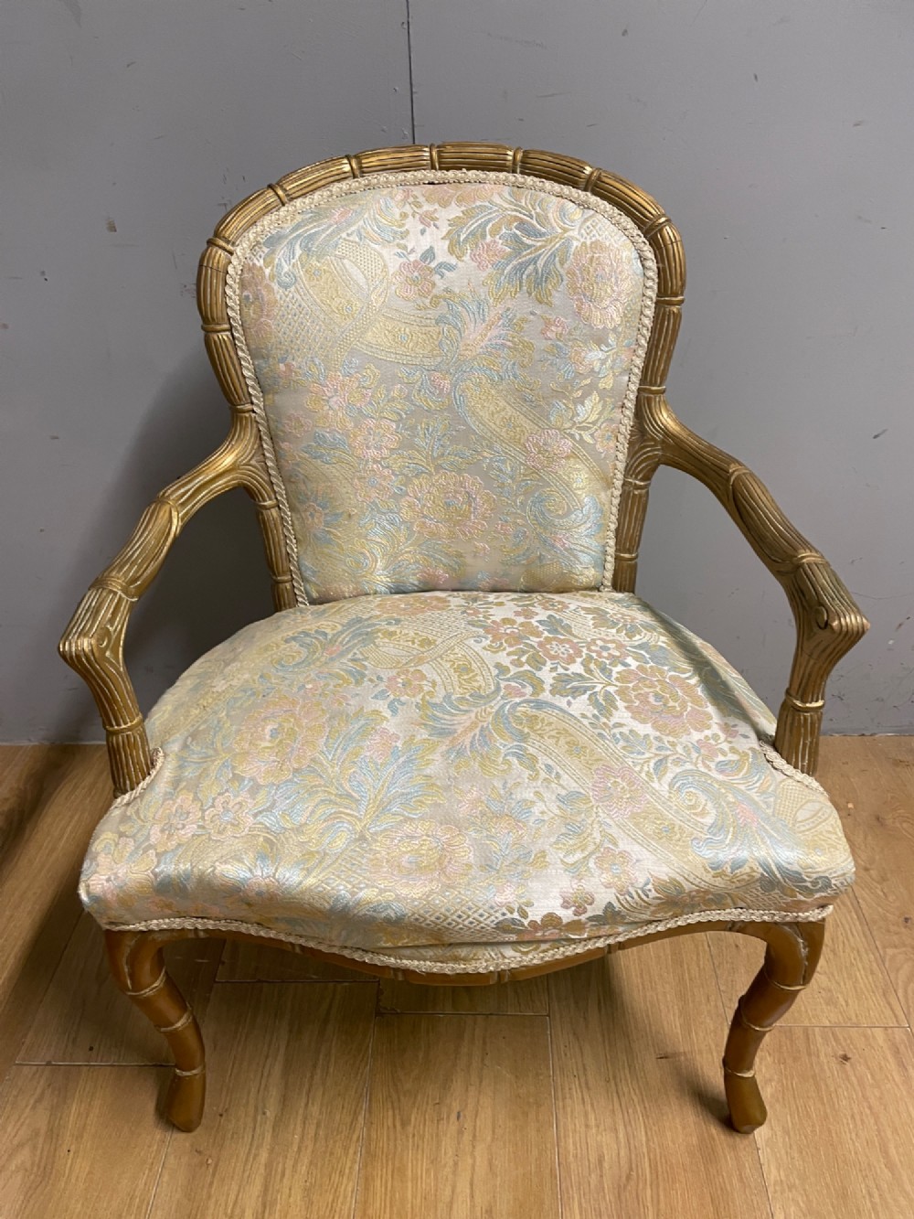 A three-piece Edwardian French style giltwood salon suite comprising a two-seater sofa and two matching armchairs upholstered in patterned cream silk fabric. View VI