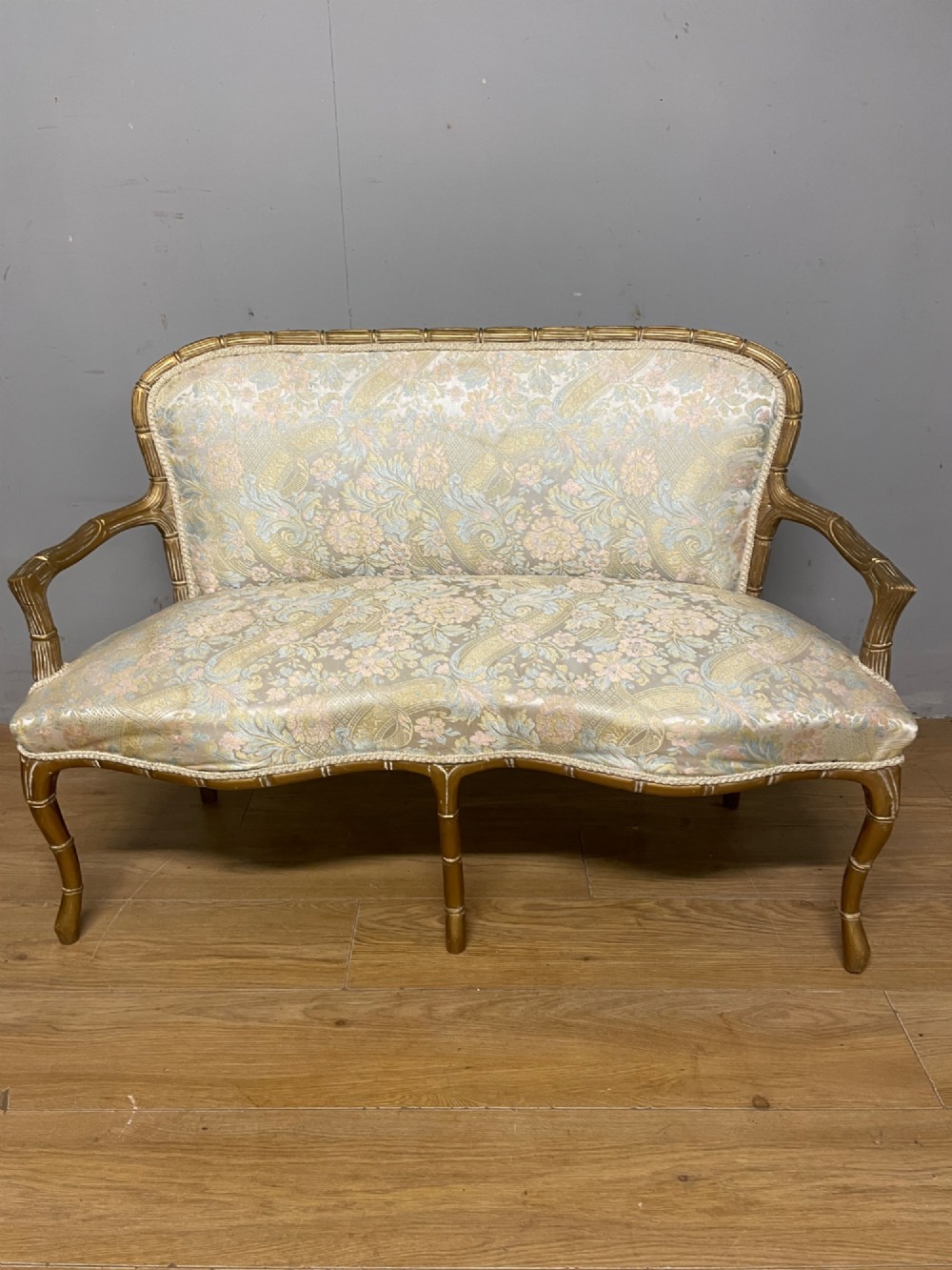 A three-piece Edwardian French style giltwood salon suite comprising a two-seater sofa and two matching armchairs upholstered in patterned cream silk fabric. View IX