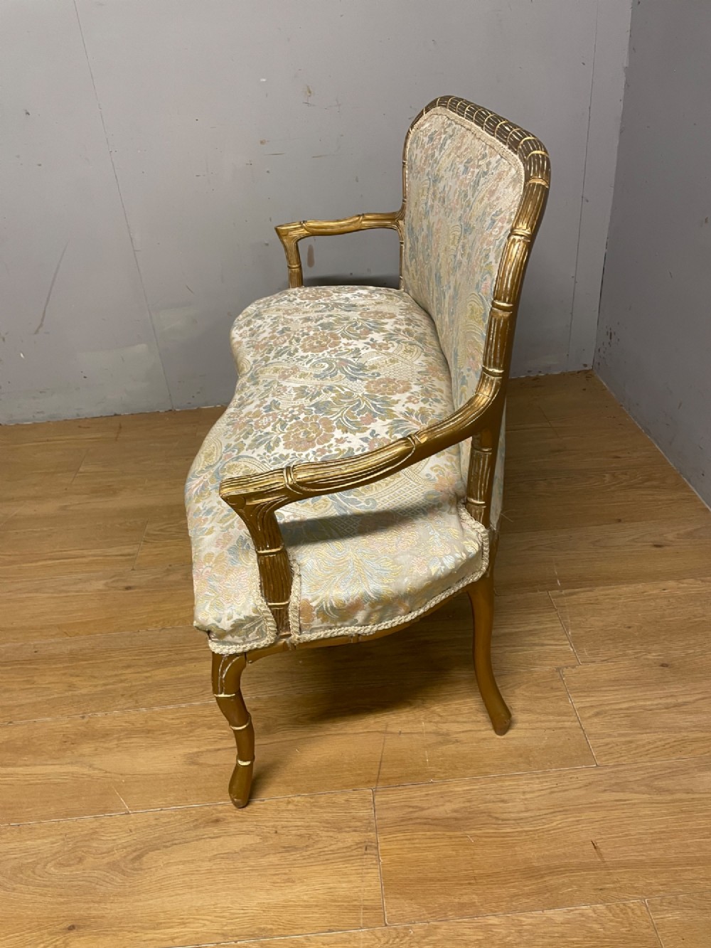 A three-piece Edwardian French style giltwood salon suite comprising a two-seater sofa and two matching armchairs upholstered in patterned cream silk fabric. View X