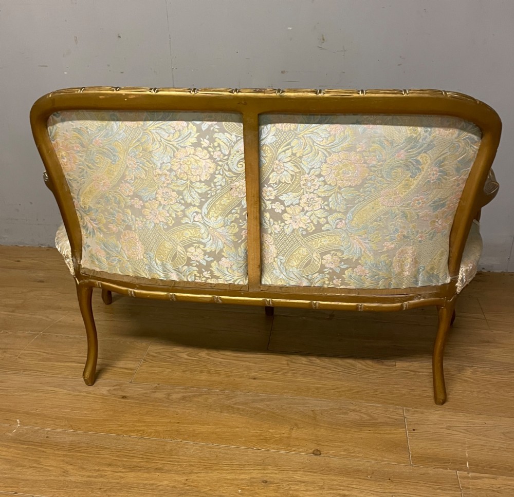 A three-piece Edwardian French style giltwood salon suite comprising a two-seater sofa and two matching armchairs upholstered in patterned cream silk fabric. View XI