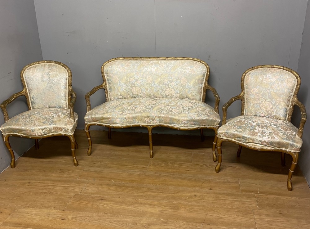 A three-piece Edwardian French style giltwood salon suite comprising a two-seater sofa and two matching armchairs upholstered in patterned cream silk fabric. View XII