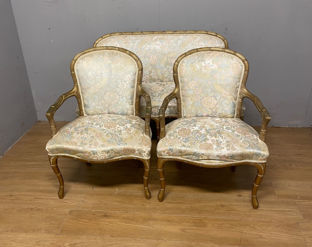 A three-piece Edwardian French style giltwood salon suite comprising a two-seater sofa and two matching armchairs upholstered in patterned cream silk fabric. View XIII