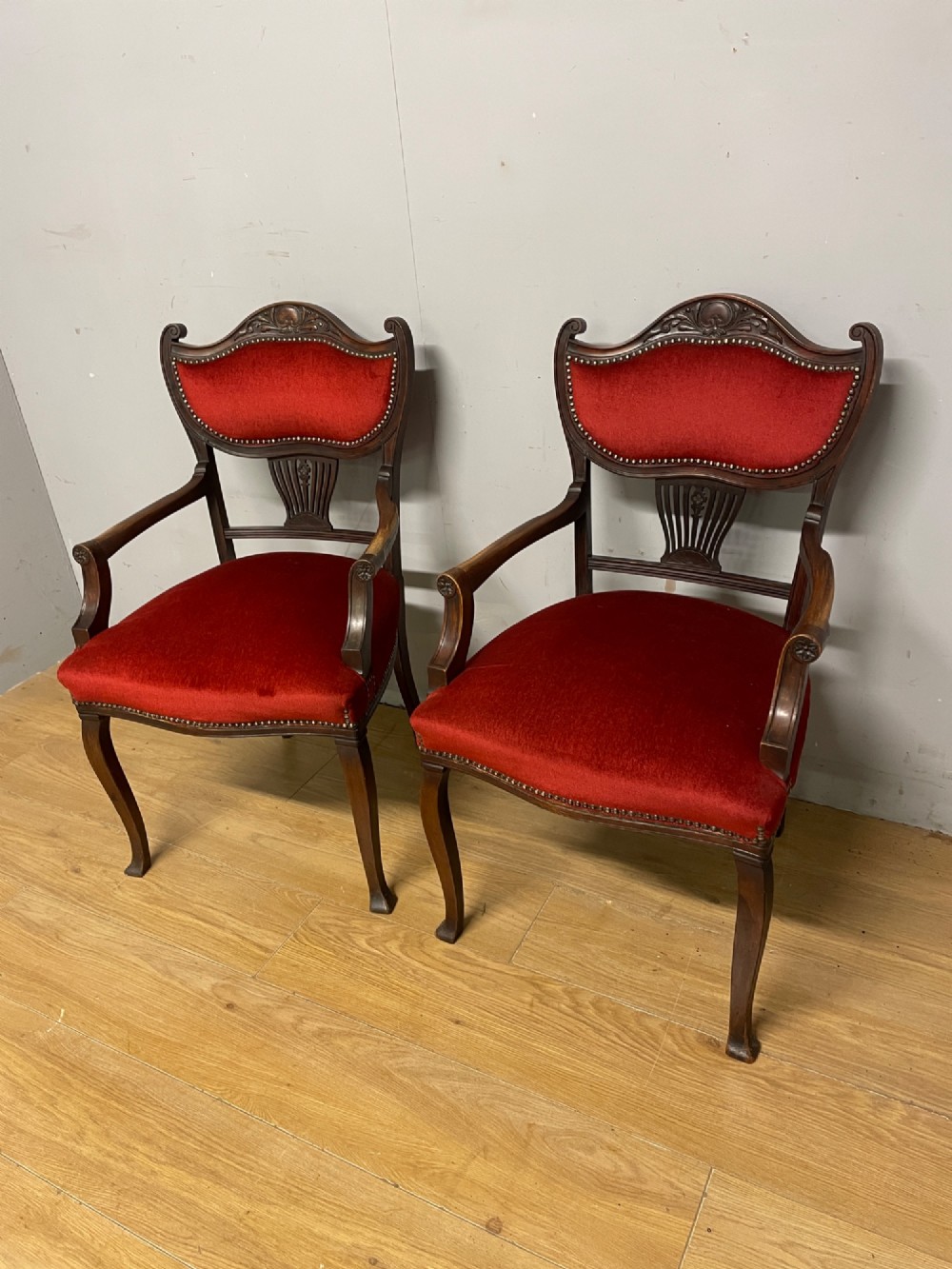 A pair of nineteenth-century Empire style mahogany armchairs upholstered in deep red velvet with decorative stud trimming. View II