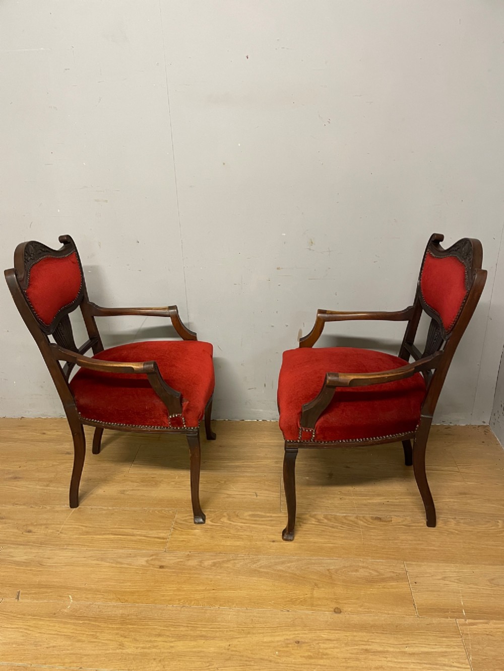 A pair of nineteenth-century Empire style mahogany armchairs upholstered in deep red velvet with decorative stud trimming. View V