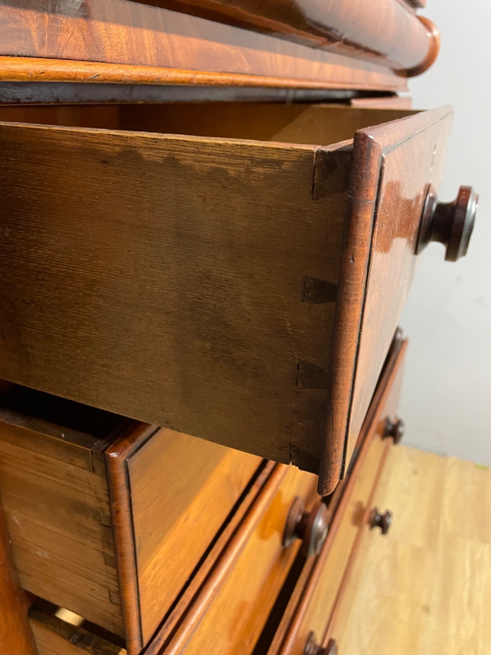 A 19th-century Scottish flame mahogany chest of drawers featuring a top cushion drawer, carved corbels, five lower drawers with turned wooden knobs, and turned feet. View VII