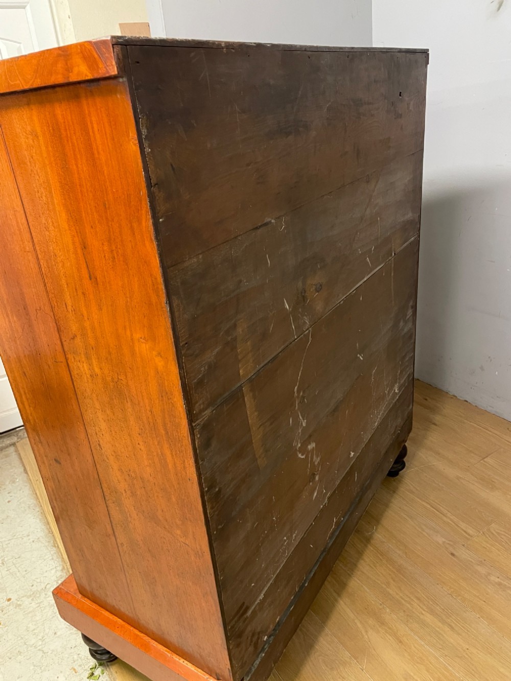 A 19th-century Scottish flame mahogany chest of drawers featuring a top cushion drawer, carved corbels, five lower drawers with turned wooden knobs, and turned feet. View X