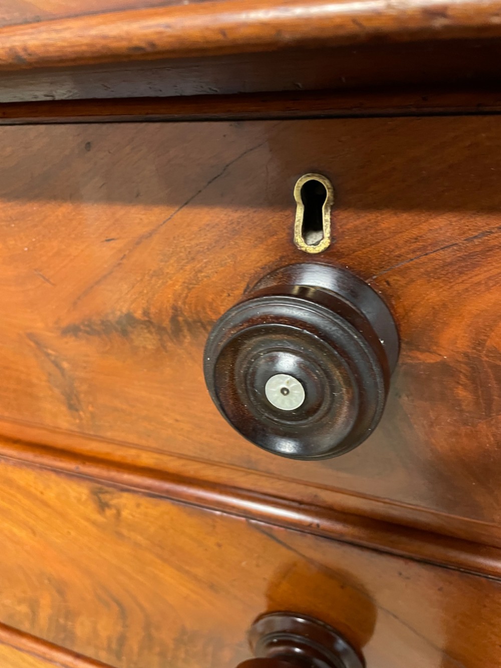 A 19th-century Scottish flame mahogany chest of drawers featuring a top cushion drawer, carved corbels, five lower drawers with turned wooden knobs, and turned feet. View XIV