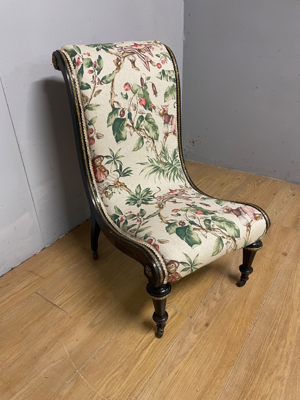 A 19th-century Aesthetic Movement slipper chair featuring an ebonised wood frame accented with gilt ormolu mounts and upholstered in botanical fabric. View IV