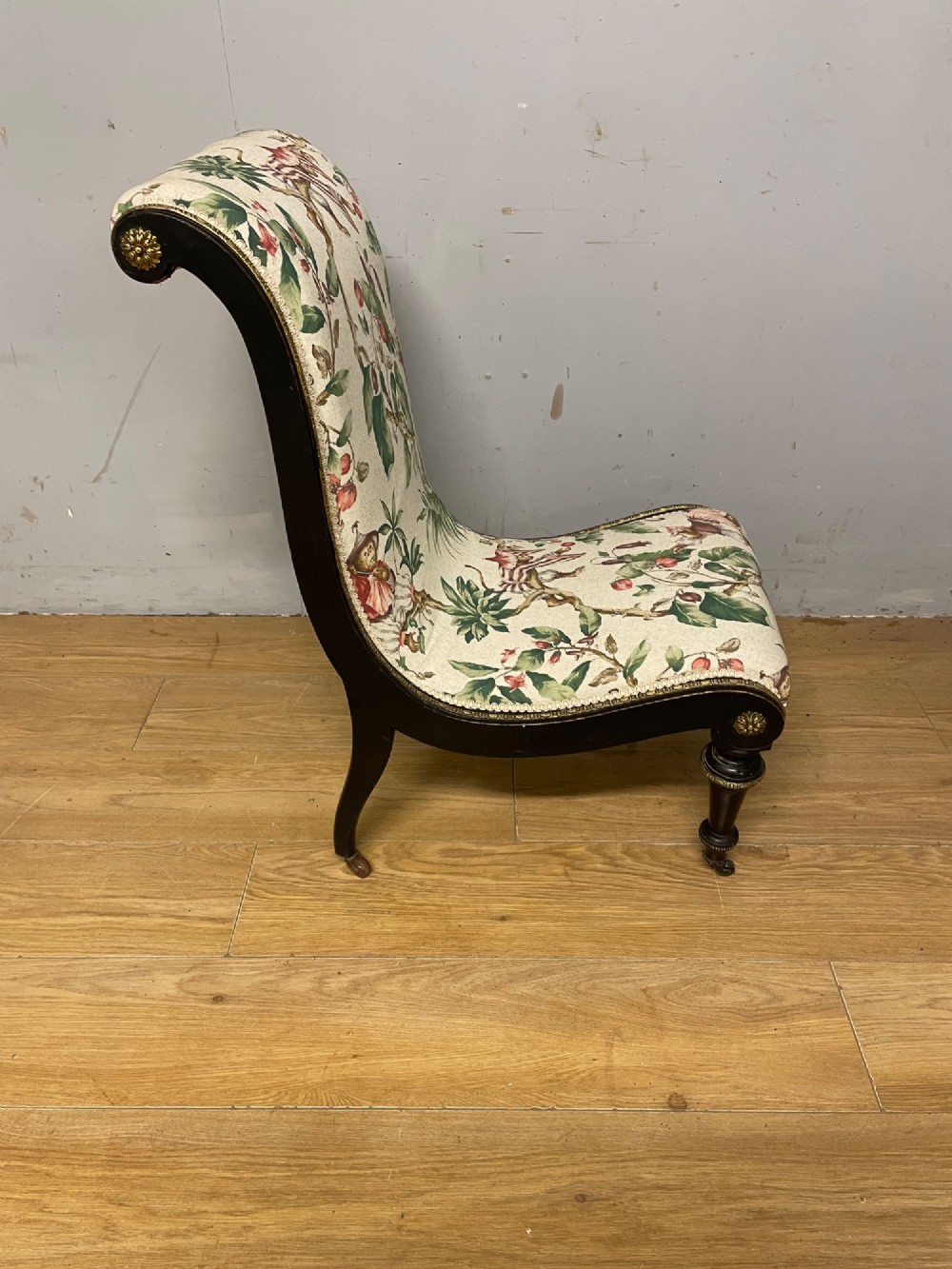 A 19th-century Aesthetic Movement slipper chair featuring an ebonised wood frame accented with gilt ormolu mounts and upholstered in botanical fabric. View VII