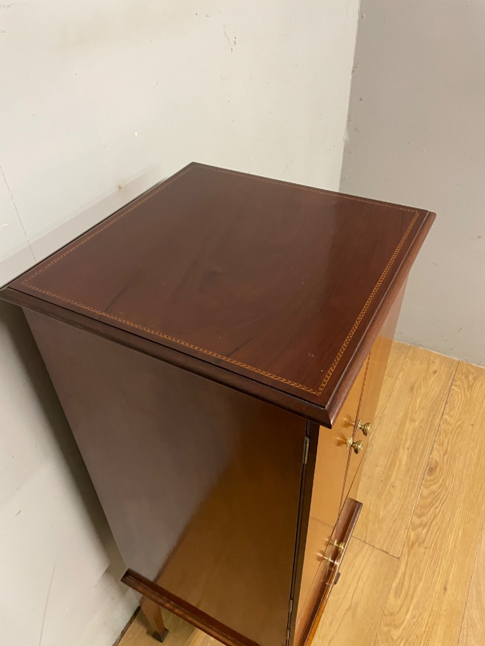 A tall slim Edwardian mahogany cabinet featuring four doors with line inlay, brass knobs, and tall tapered legs. View III