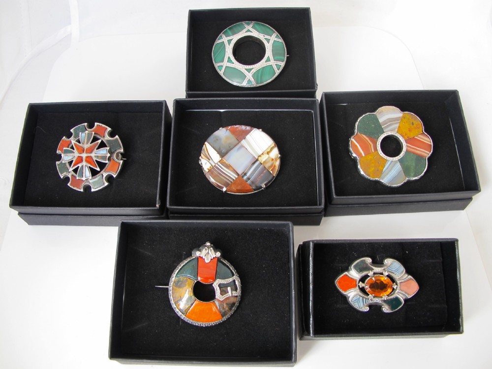 A circular Victorian Scottish silver brooch inlaid with segmented orange, green, and brown agate stones featuring an engraved silver buckle motif. View V