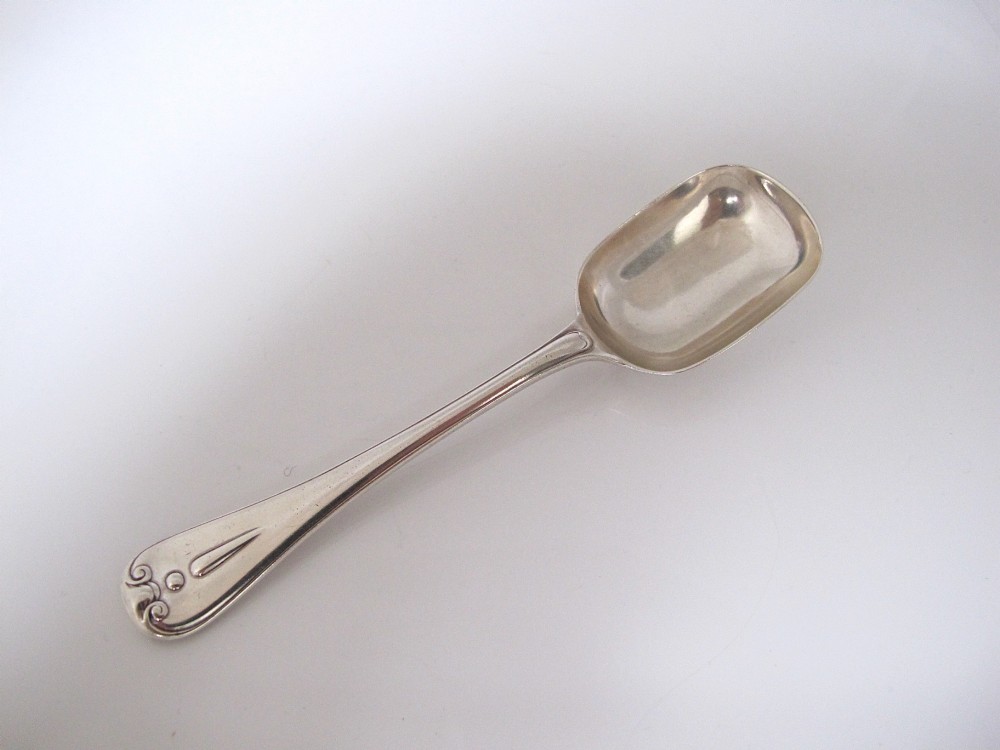 A Victorian sterling silver jam spoon featuring a shovel-shaped rectangular bowl and a decorated Hanoverian pattern handle with scroll terminal.