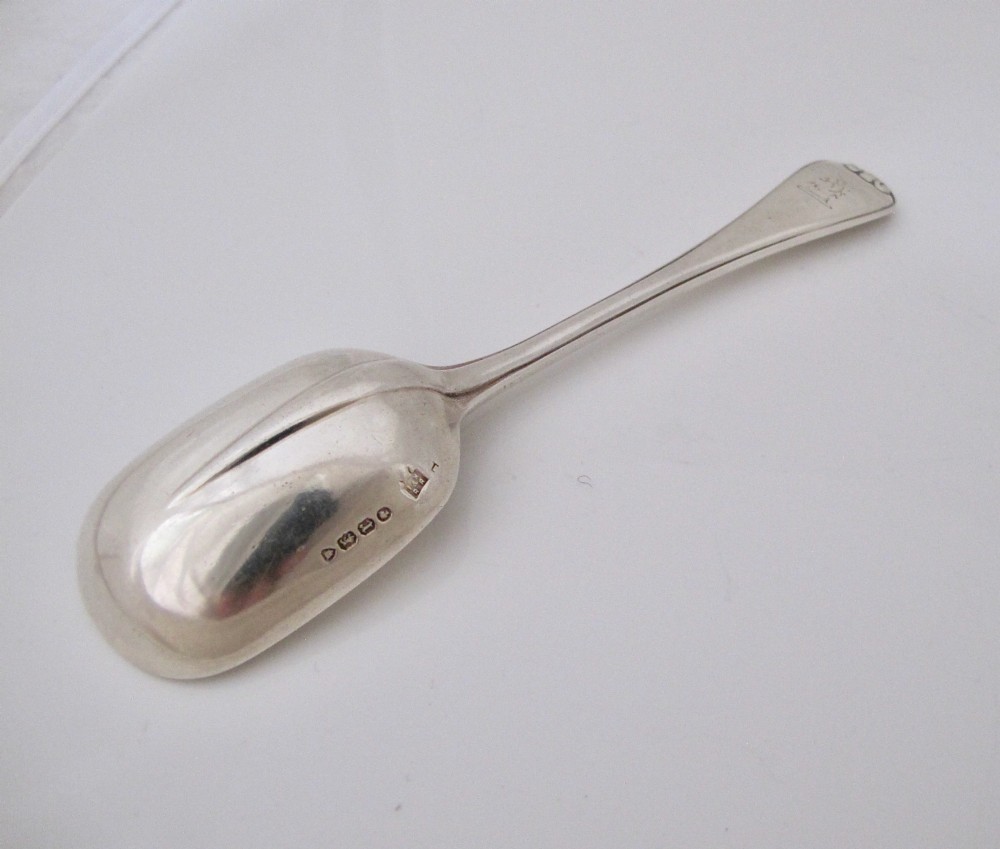 A Victorian sterling silver jam spoon featuring a shovel-shaped rectangular bowl and a decorated Hanoverian pattern handle with scroll terminal. View V