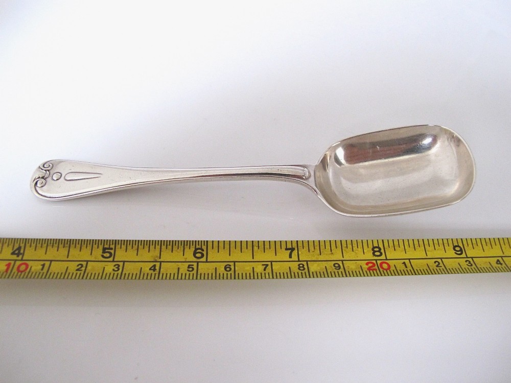 A Victorian sterling silver jam spoon featuring a shovel-shaped rectangular bowl and a decorated Hanoverian pattern handle with scroll terminal. View VII