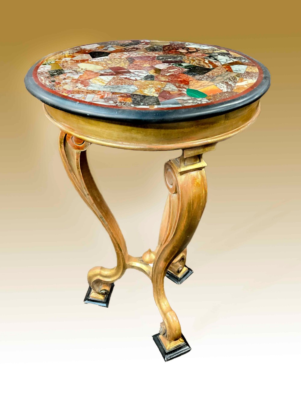 A circular Victorian specimen table featuring a colourful inlaid marble mosaic top on curved giltwood legs.