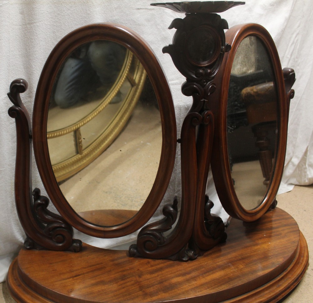 An antique Victorian carved mahogany dressing table mirror with dual oval adjustable mirrors on a central carved column and curved wooden base. View II