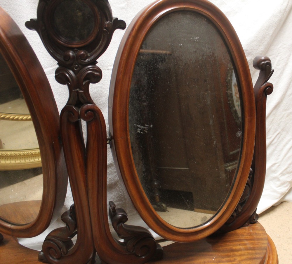 An antique Victorian carved mahogany dressing table mirror with dual oval adjustable mirrors on a central carved column and curved wooden base. View III