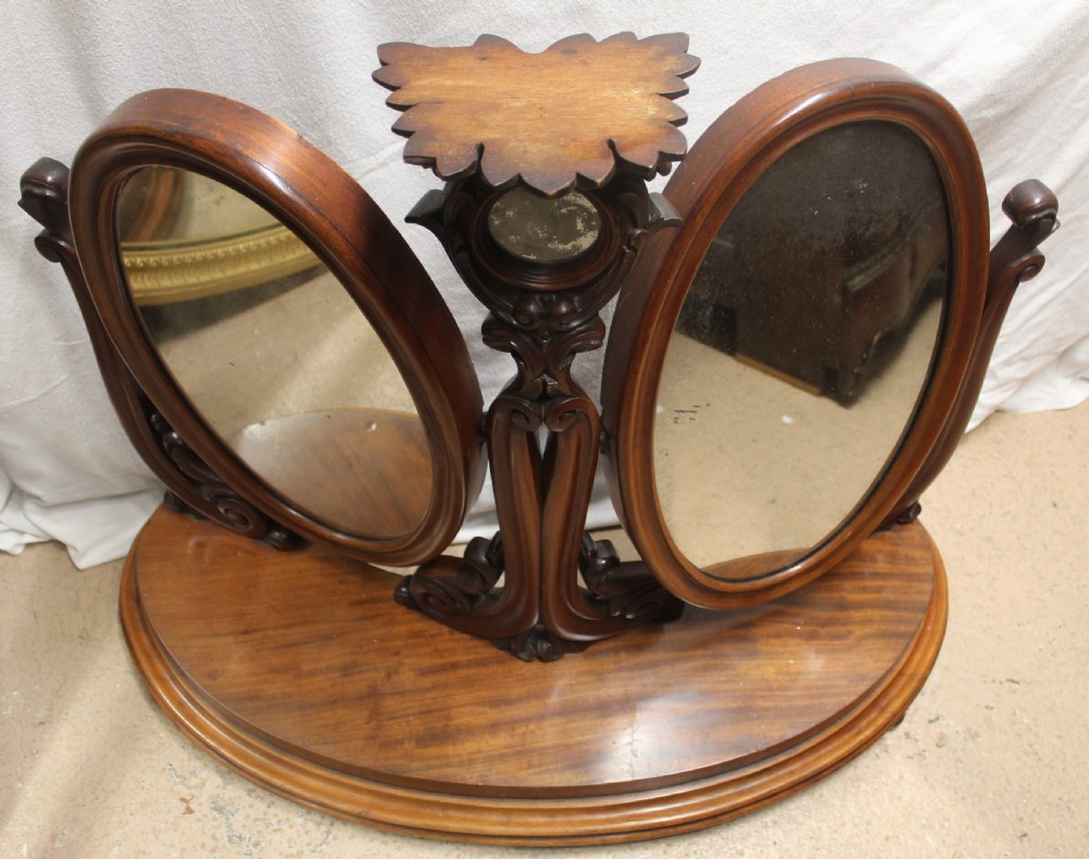 An antique Victorian carved mahogany dressing table mirror with dual oval adjustable mirrors on a central carved column and curved wooden base. View V