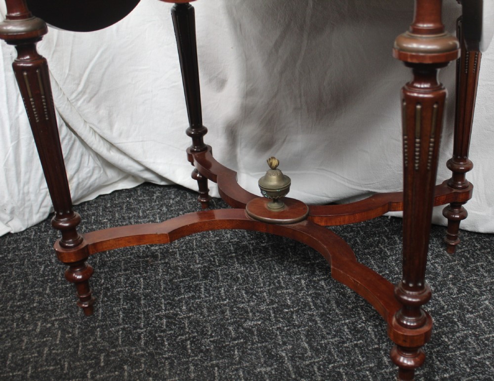 An antique French mahogany side table with brass mounts, inlaid top design, turned fluted legs, and a curved X-stretcher with a brass urn finial. View II