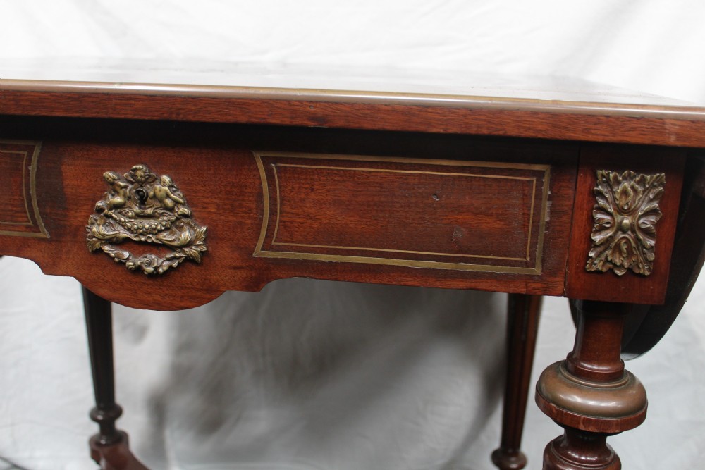 An antique French mahogany side table with brass mounts, inlaid top design, turned fluted legs, and a curved X-stretcher with a brass urn finial. View III