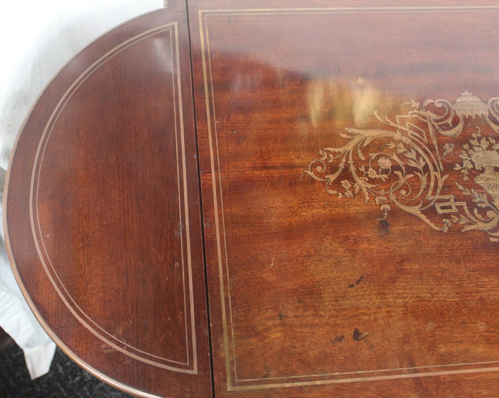 An antique French mahogany side table with brass mounts, inlaid top design, turned fluted legs, and a curved X-stretcher with a brass urn finial. View VII