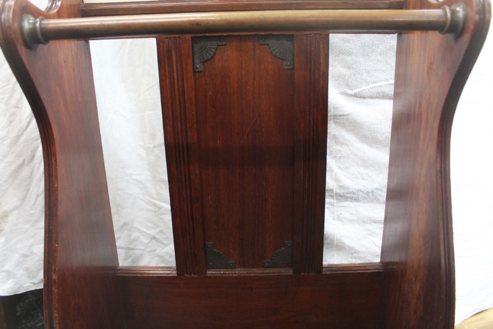 A late Victorian dark oak stick stand featuring a brass retaining bar, ceramic tile insert decorated with yellow lilies and an urn motif, and a removable black cast iron drip tray at the base. View IV