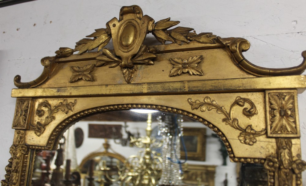 A pair of gilded Neoclassical wall mirrors featuring decorative top cresting, beaded frames, and integrated candle sconces at the base. View IV